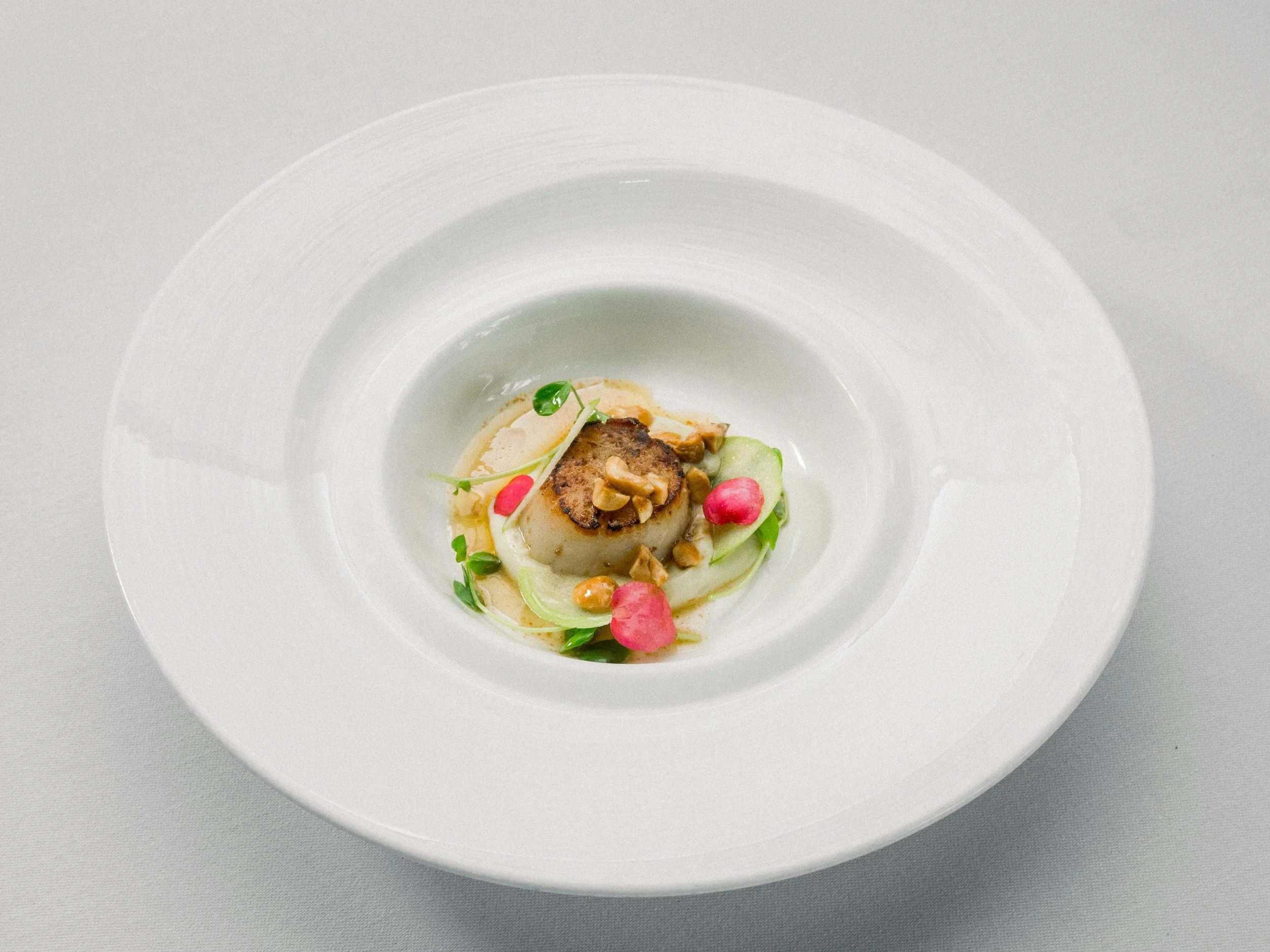 Course two: a hand-dived scallop seared golden and plated with celery root, preserved lemon, and toasted hazelnut
